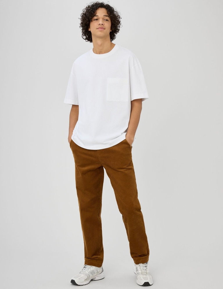 Homme portant un pantalon en velours côtelé avec un t-shirt blanc oversized et des baskets blanches