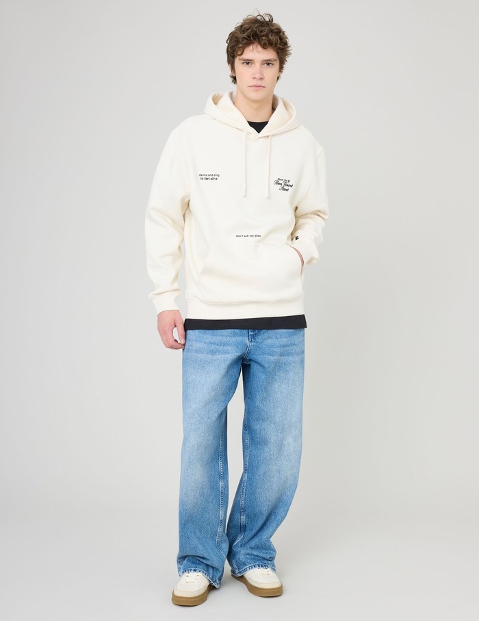 Look minimaliste homme avec sweat à capuche blanc zippé, t-shirt kaki et jean brut