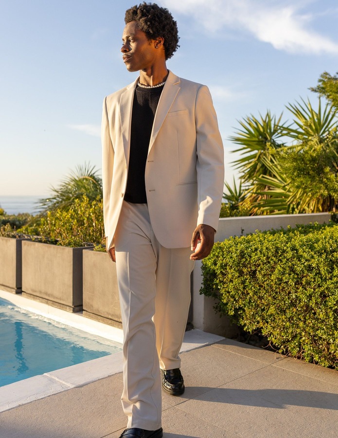 Look semi-formel avec haut tricoté noir sous blazer et pantalon costume beige assortis, mocassins noirs et collier discret