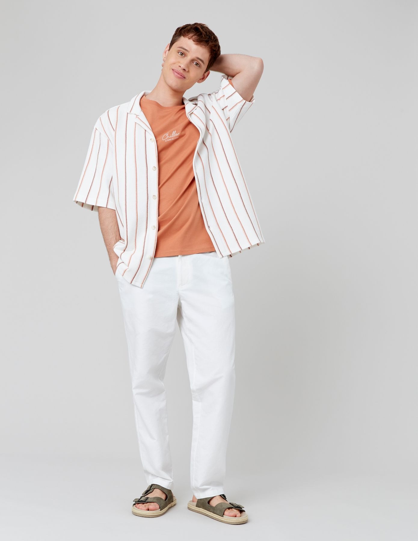 Look preppy estival avec t-shirt orange sous chemise rayée et pantalon blanc