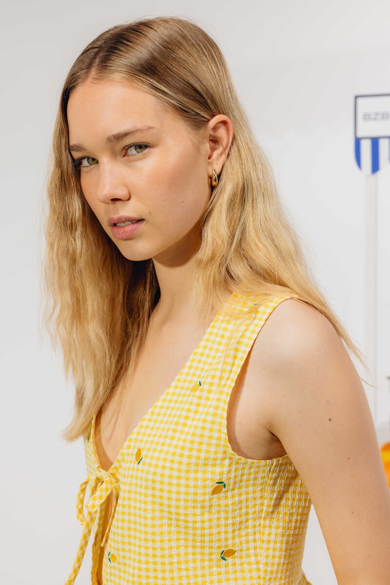 Robe estivale en imprimé vichy jaune vif à petits motifs citrons verts avec décolleté plongeant noué, incarnant l'esprit solaire des vacances d'été