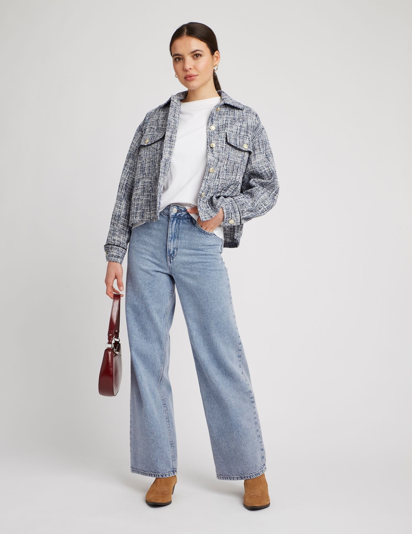 Style urbain avec t-shirt blanc, jean large délavé, veste texturée à carreaux et sac structuré