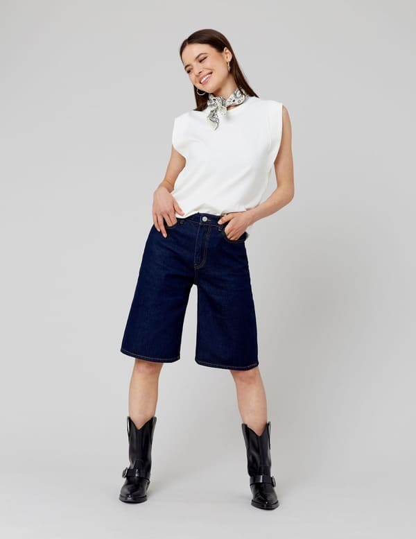 Style rock avec bermuda en jean brut, débardeur blanc, foulard imprimé et bottes noires