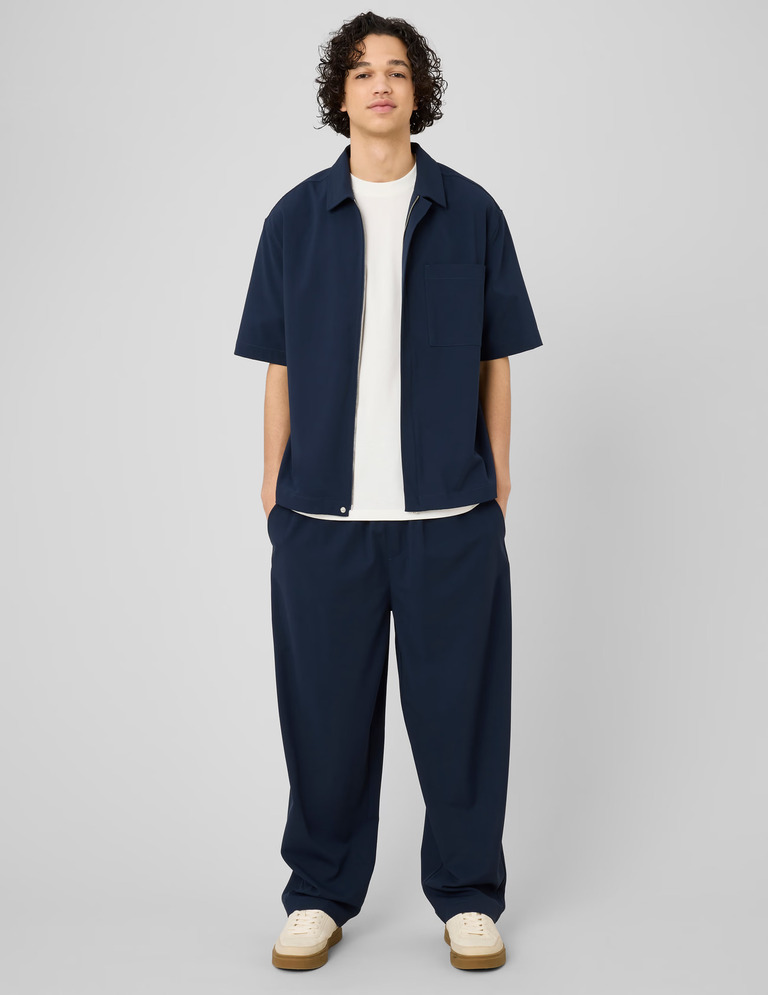 Look homme coordonné bleu marine avec pantalon ample, t-shirt blanc et surchemise zippée