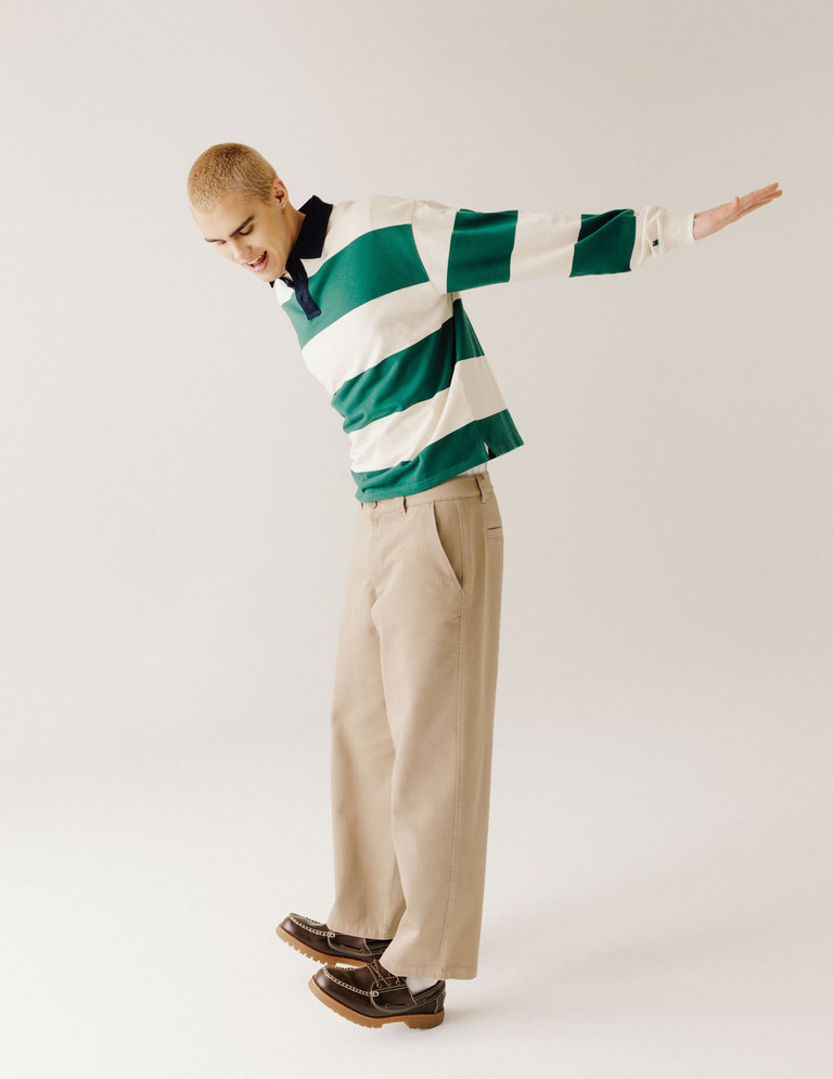 Look homme avec pantalon large beige, polo rugby rayé vert et écru et chaussures marron
