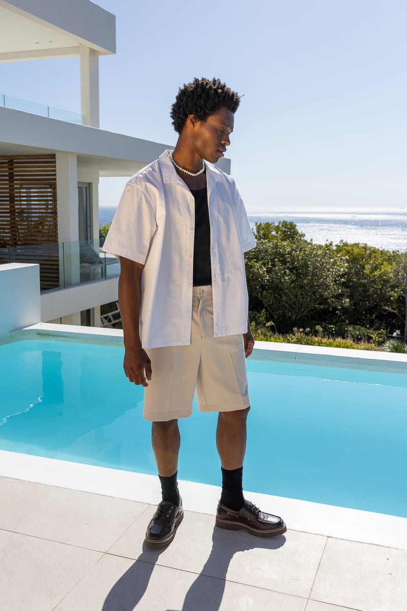 Style preppy chic avec chemise blanche ouverte et short beige