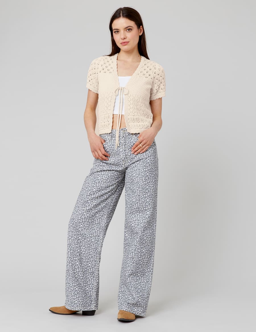 Pantalon wide leg imprimé léopard avec cardigan crochet crème noué à la taille, bralette blanc et boots caramel