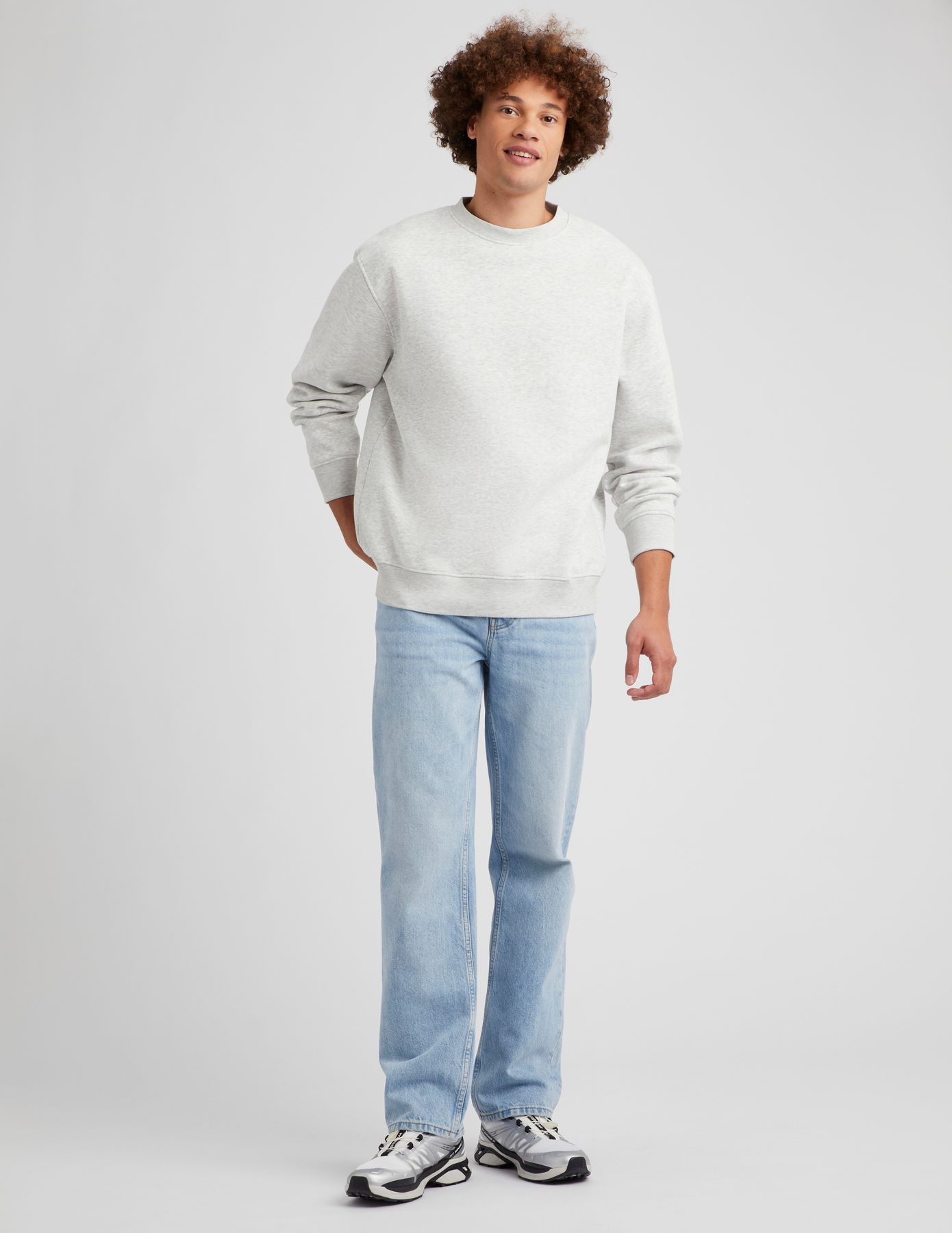 Sweat col rond oversize gris chiné avec jean baggy bleu clair délavé et sneakers de running