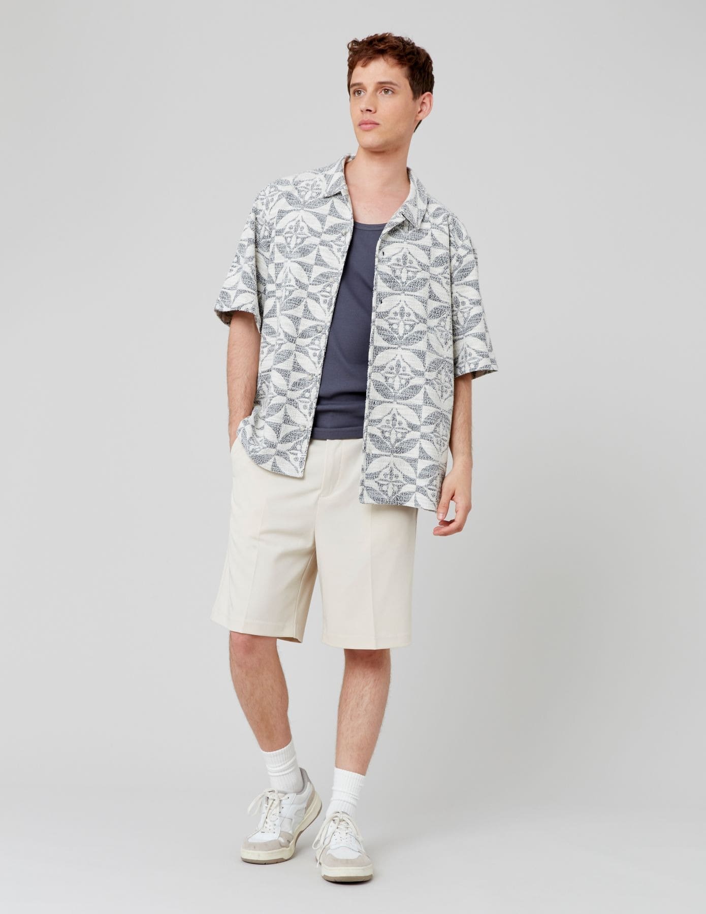 Look audacieux avec chemisette à motifs géométriques traditionnels, bermuda crème et baskets blanches