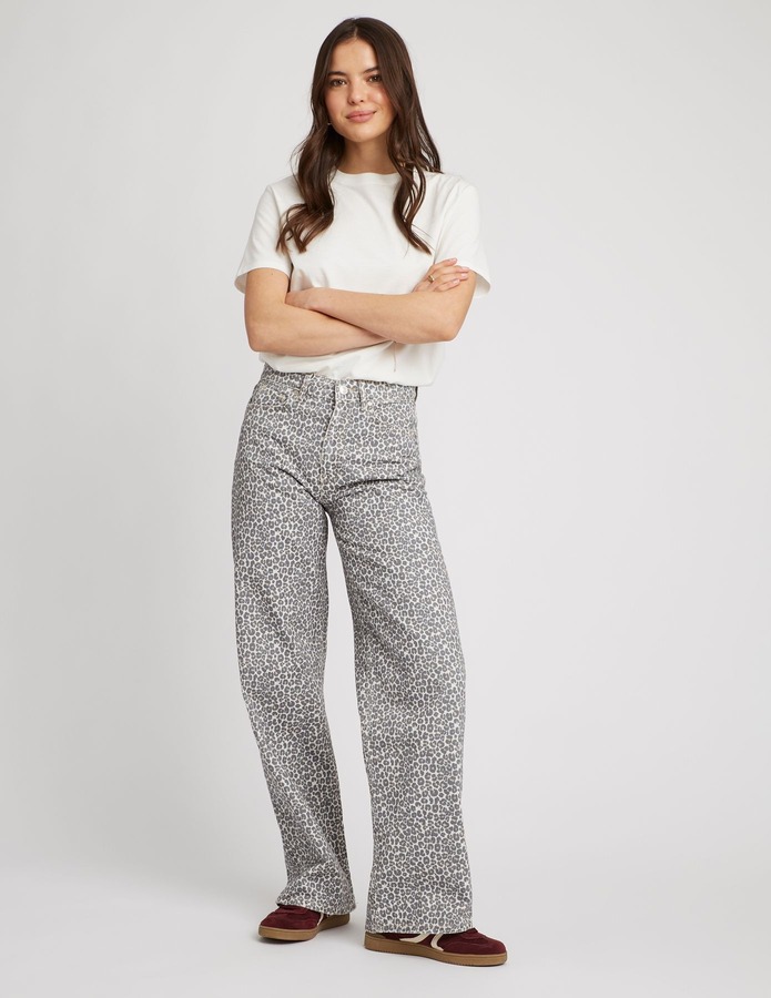 Jean wide leg imprimé léopard gris et blanc associé à un t-shirt basique blanc et des baskets bordeaux