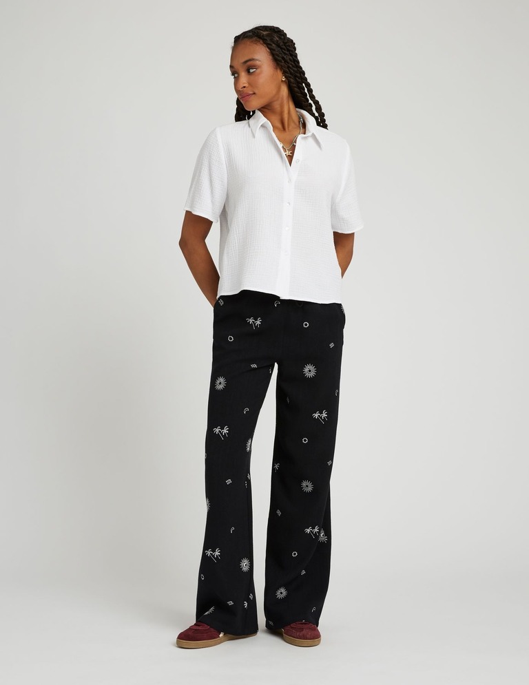 Tenue avec chemise blanche et pantalon imprimé tropical avec baskets colorées