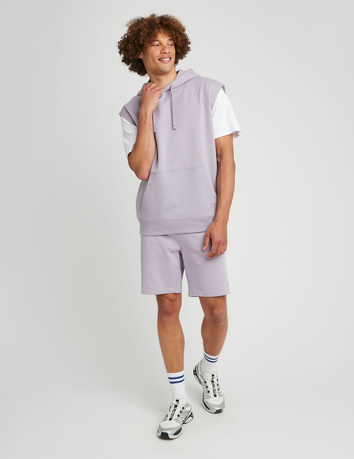 Look sportswear avec bermuda lilas, sweat à capuche sans manches et baskets blanches