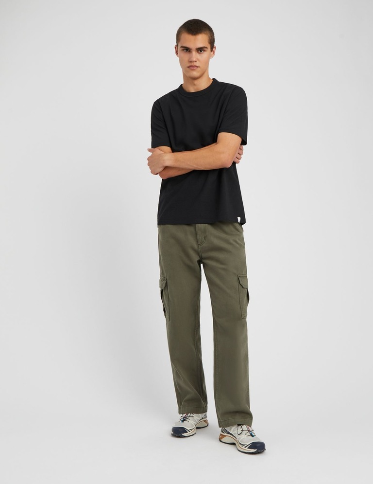 Tenue streetwear avec pantalon cargo kaki, t-shirt noir et baskets de running