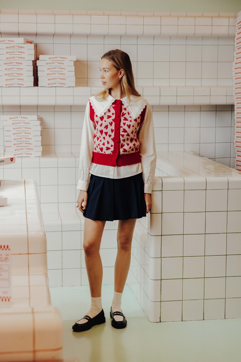 Style preppy avec chemise blanche, gilet à motifs et jupe plissée