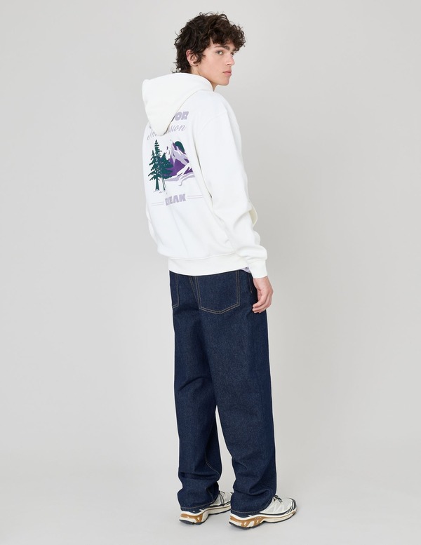 Hoodie blanc à imprimé graphique montagne dans le dos associé à un jean large indigo brut et sneakers trail à semelles crantées