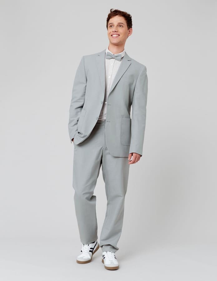 Costume gris clair porté avec une chemise blanche boutonnée, un nœud papillon et des sneakers blanches