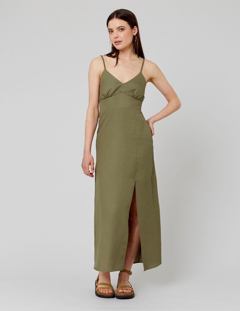 Robe longue kaki à bretelles fines avec corsage baleines, décolleté en V et fente sur le devant, portée avec des sandales plates kaki pour un look monochrome élégant