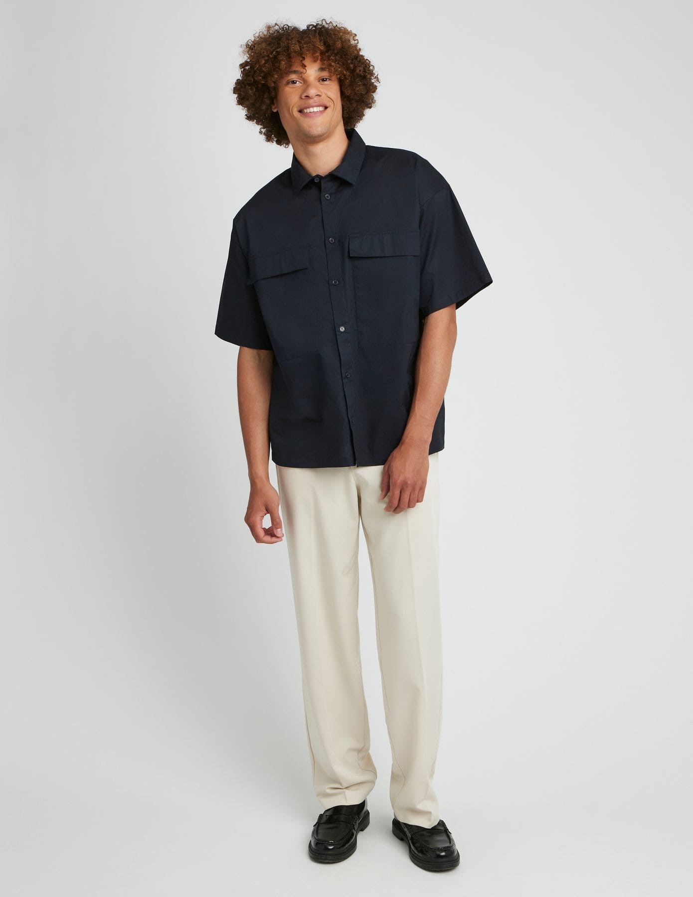 Style preppy avec chemisette navy oversize, pantalon crème large et mocassins noirs