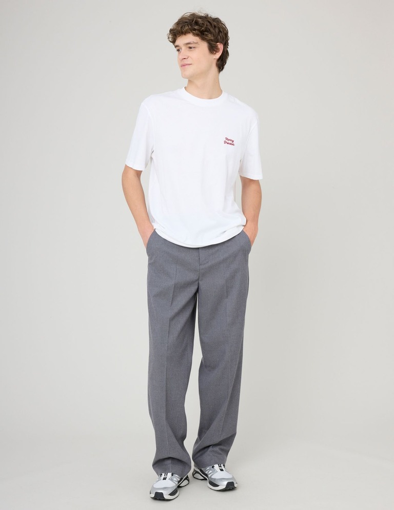 Look avec pantalon de ville gris associé à un t-shirt blanc et baskets pour un style décontracté chic