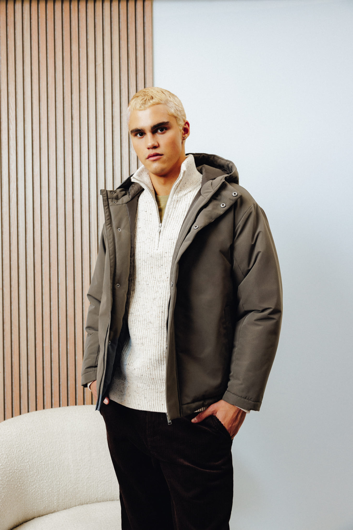 Style urbain avec pull beige à col zippé sous parka kaki et pantalon noir