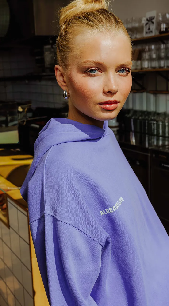 Bermuda long porté avec une veste en tissu enduit, un sweat à capuche imprimé et un t-shirt imprimé