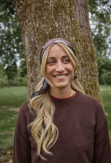 Portrait de Clara souriante, bandeau dans les cheveux et pull chocolat