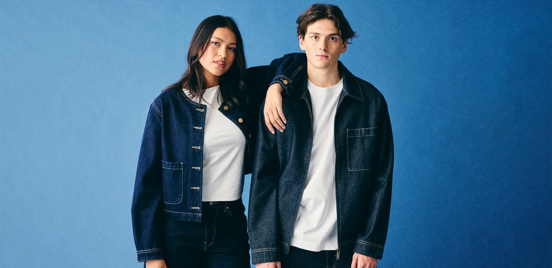 Deux jeunes en veste en jean brut et t-shirt blanc sur fond bleu