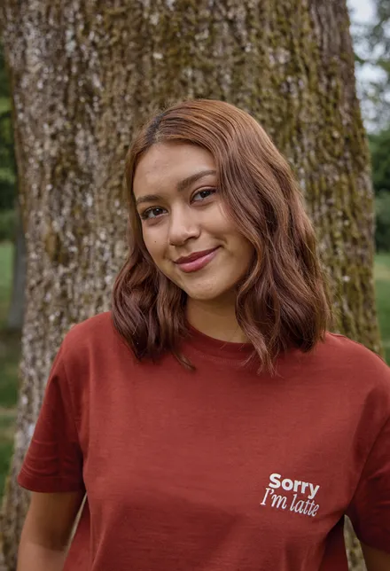 Portrait d’Eva, en t-shirt rouille imprimé Sorry I’m latte