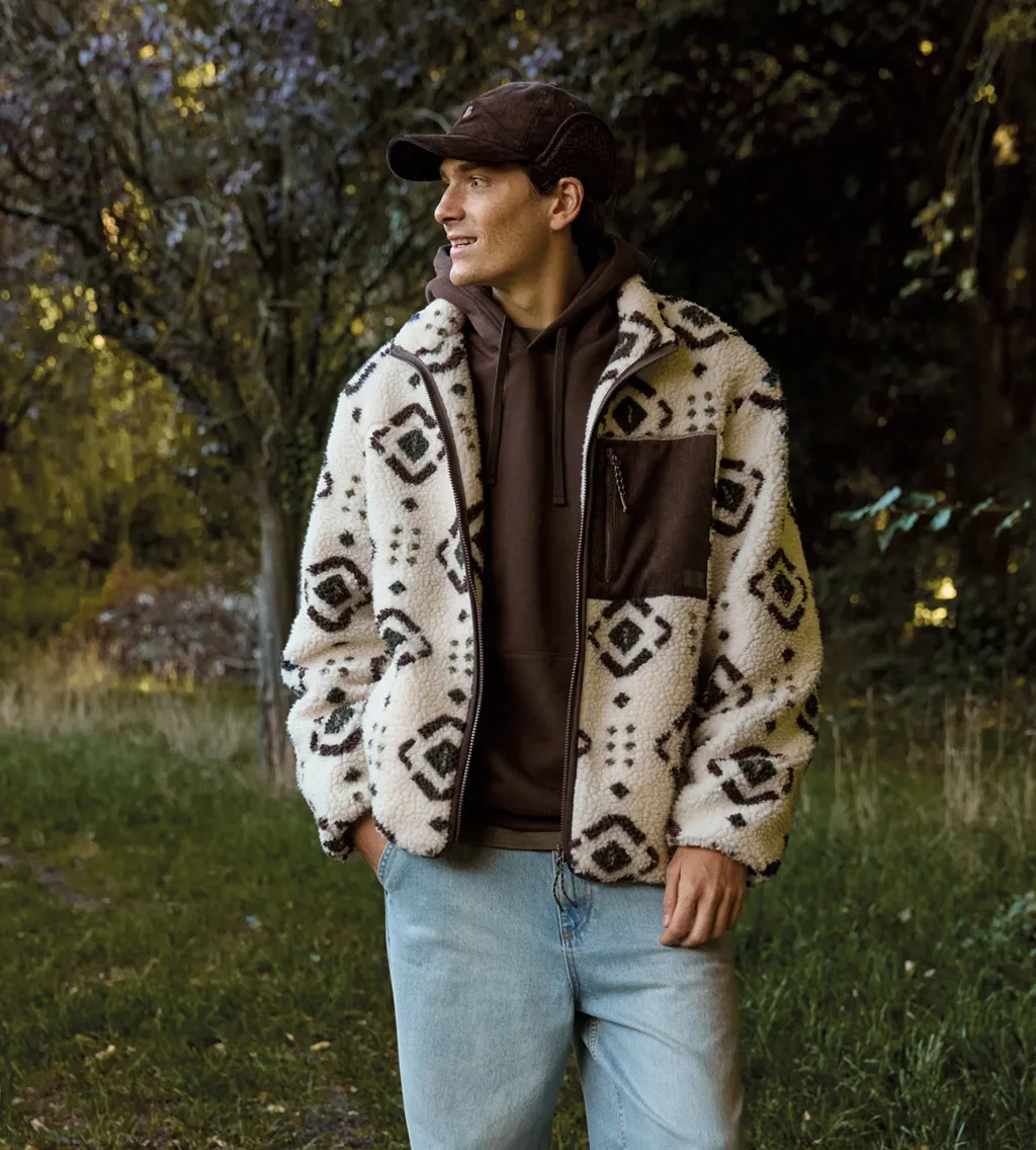 Garçon en veste sherpa à motifs et casquette dans une forêt d’automne